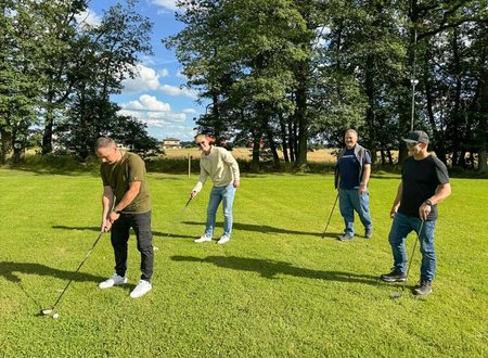 vier Unterschütz Mitarbeiter stehen auf einer Wiese und spielen Crossgolf