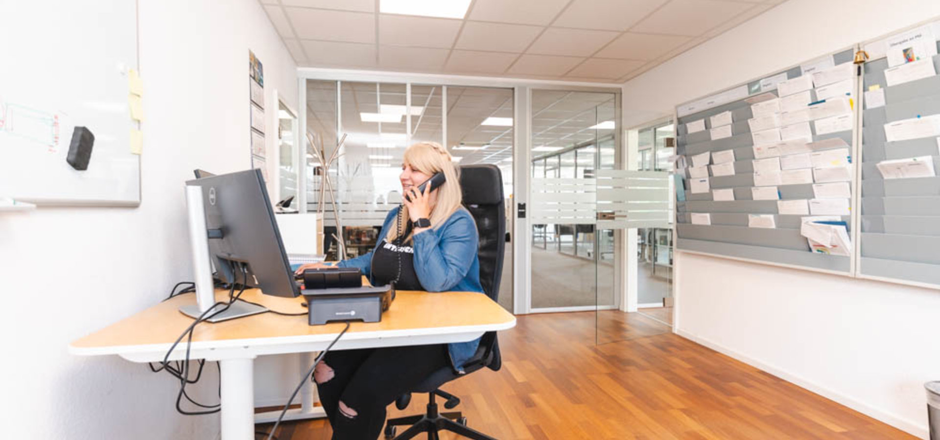 junge Service-Mitarbeiterin sitzt im Büro und telefoniert