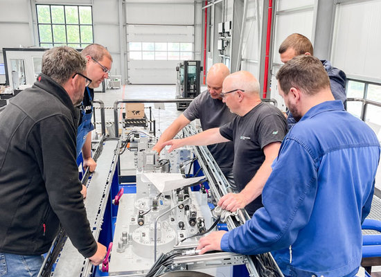mehrere Unterschütz-Mitarbeiter im Gespräch, gebeugt über eine Großhydraulik