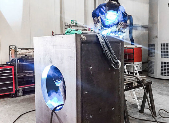 Schweißer auf großer Metallkomponente beim Schweißen