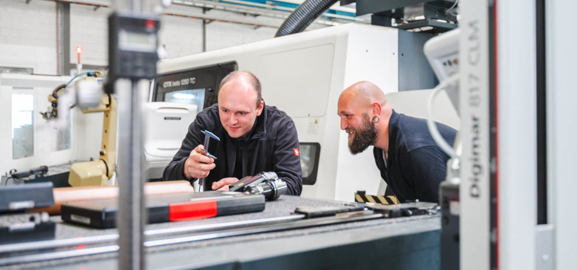 zwei Unterschütz Mitarbeiter sehen sich CNC-Werkzeuge an und planen die weitere Verarbeitung der Werkstücke