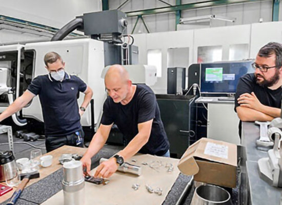 Drei Unterschütz Mitarbeiter bei der technischen Besprechung und Bauteilprüfung an CNC-Anlage