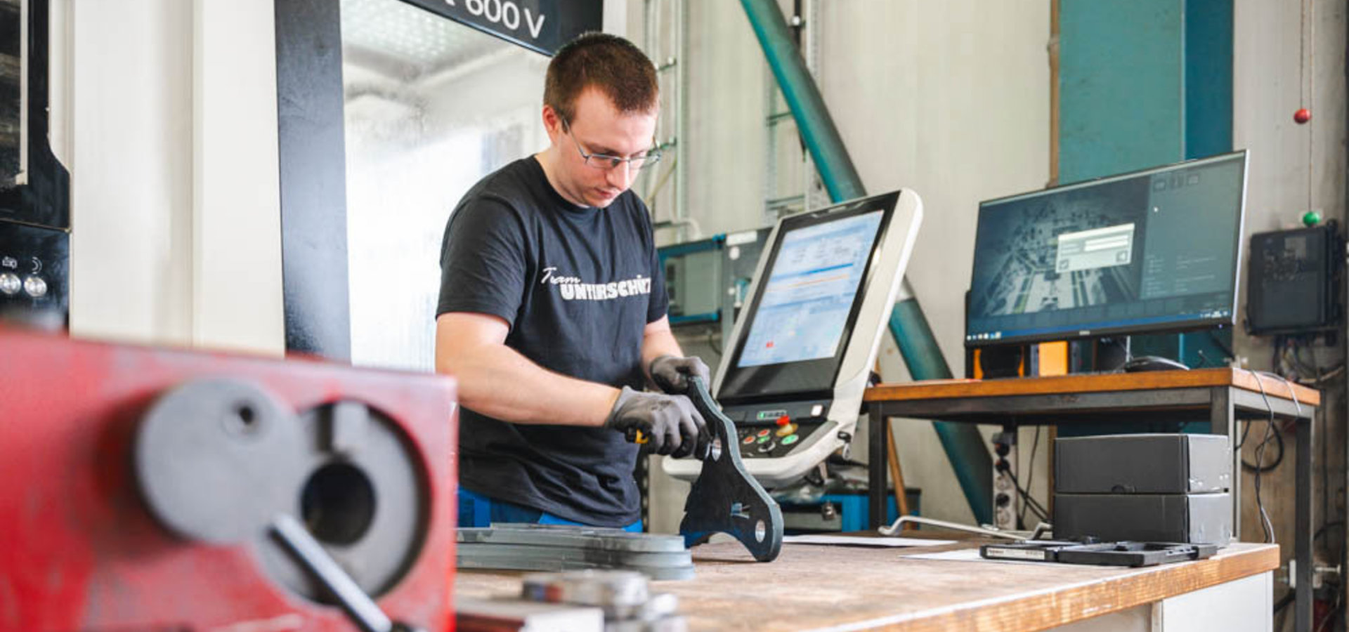 Unterschütz Mitarbeiter bearbeitet ein Werkstück vor einer CNC-Anlage