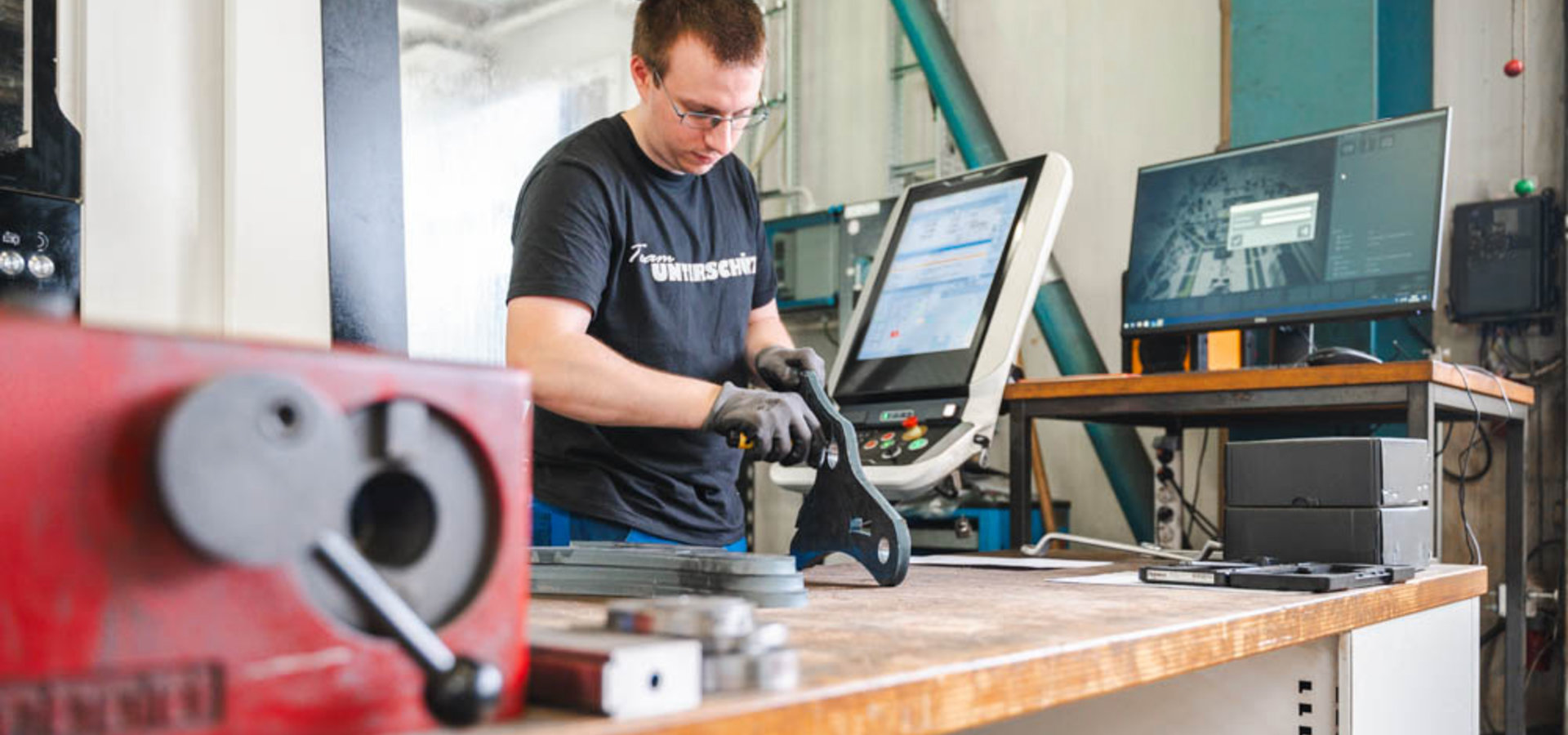 Unterschütz Mitarbeiter bearbeitet ein Werkstück vor einer CNC-Anlage