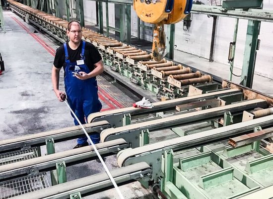 Unterschütz Mitarbeiter steht hinter einer Anlage mit Förderbandkörpern in einer Halle